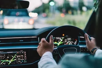 Fahrer hält das Lenkrad eines Autos mit Navigationssystem und Verkehr vor dem Fahrzeug.